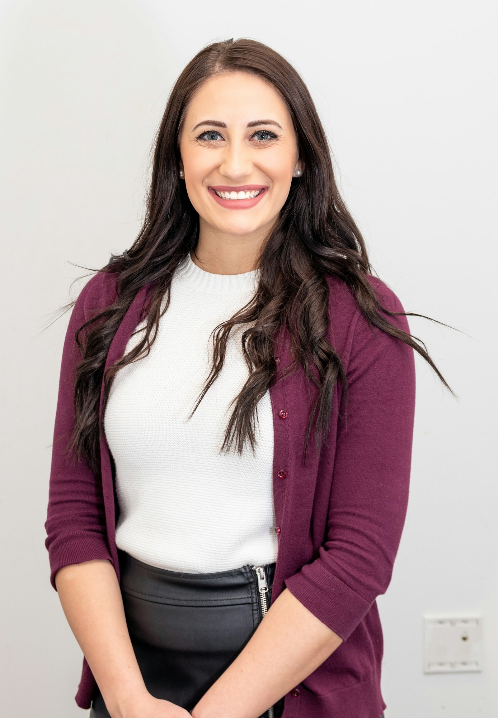 A smiling woman in a red cardigan